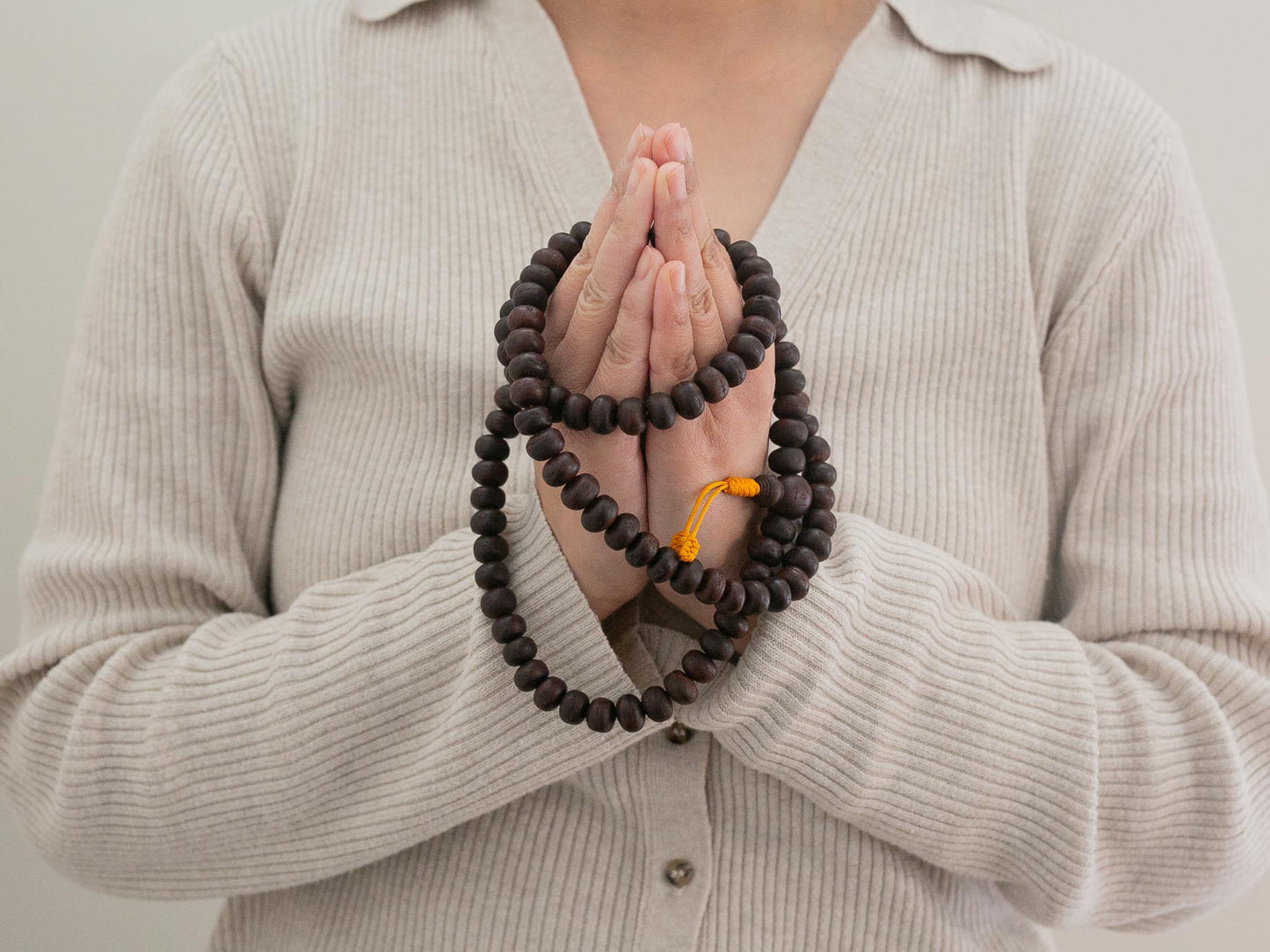 Person holding Bodhi prayer beads with a neutral background