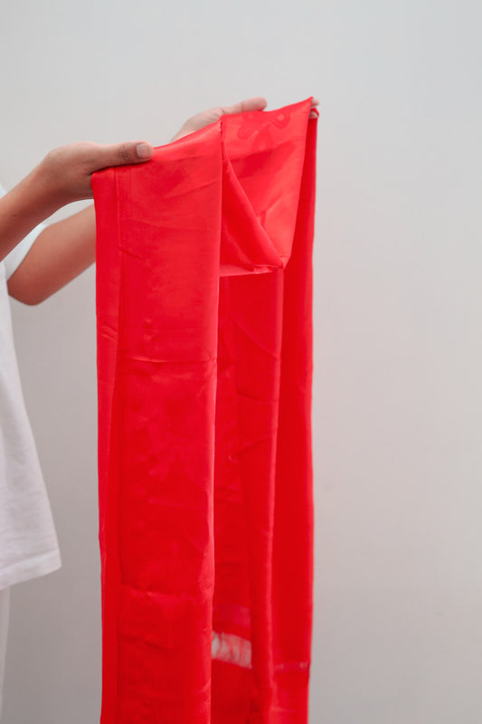 red khata scarf held in hand in an offering gesture.