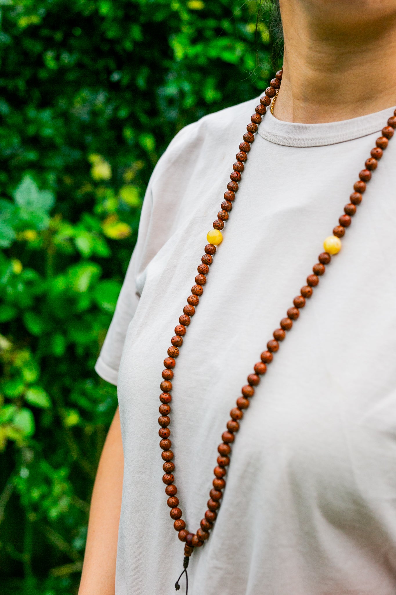 Lotus seed and amber mala worn around woman's neck