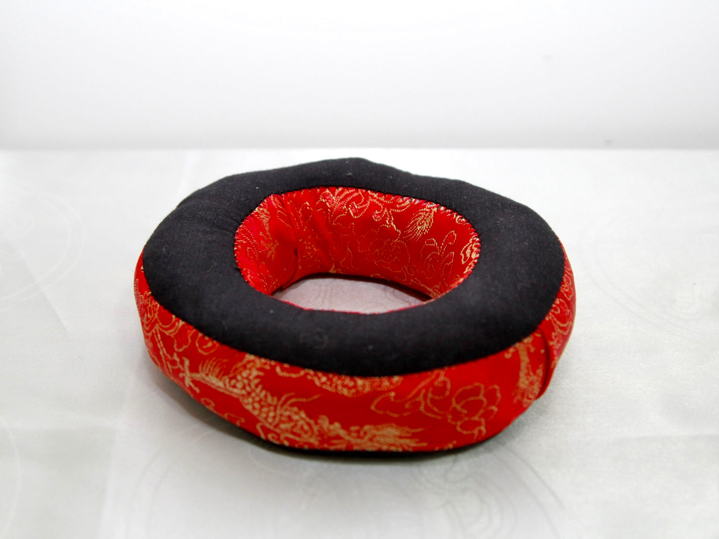 Red singing bowl cushion sitting against white background.