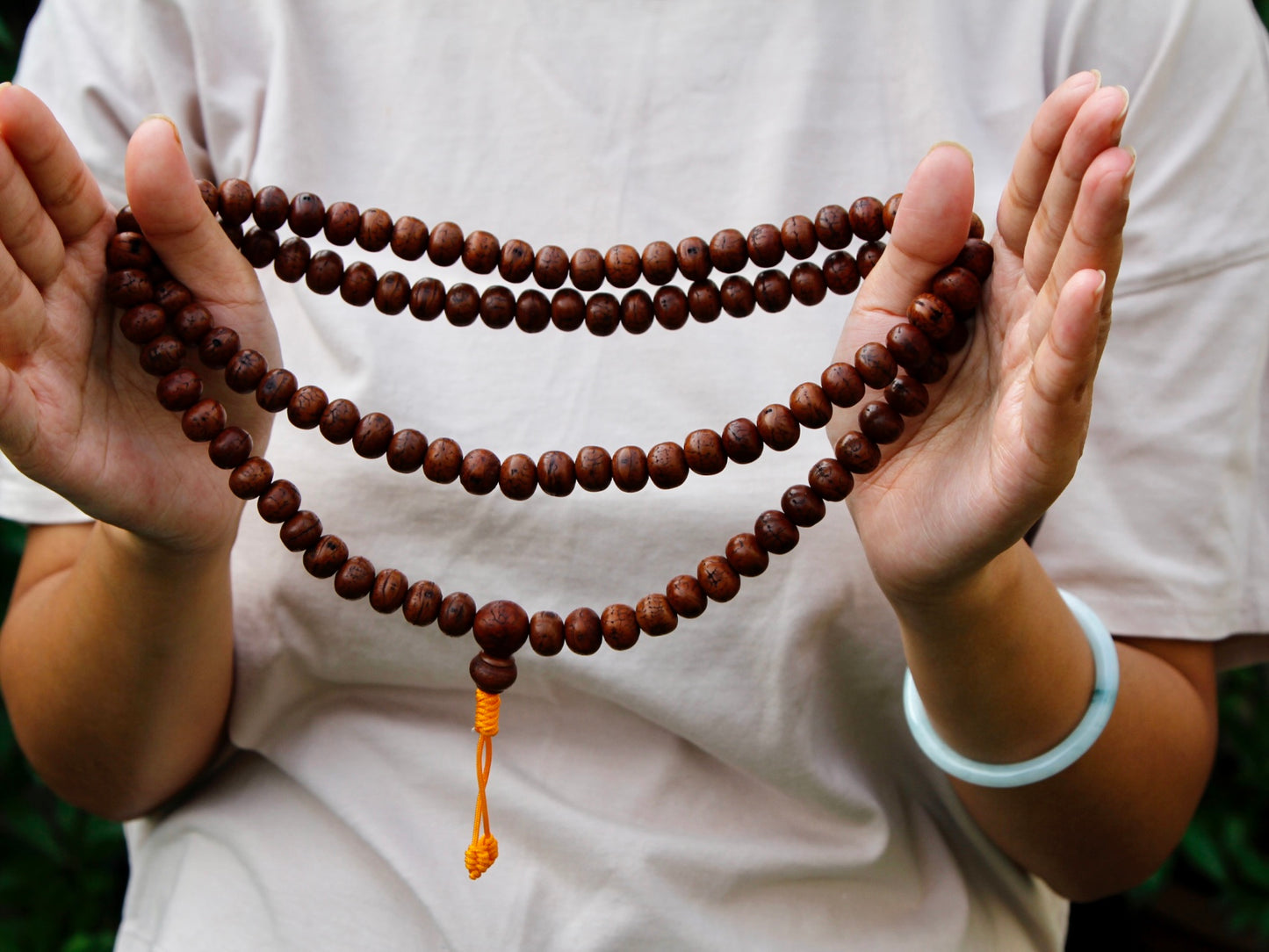 Bodhi mala stretched between 2 hands.