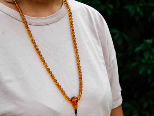 Honey amber mala worn around neck to show length of mala