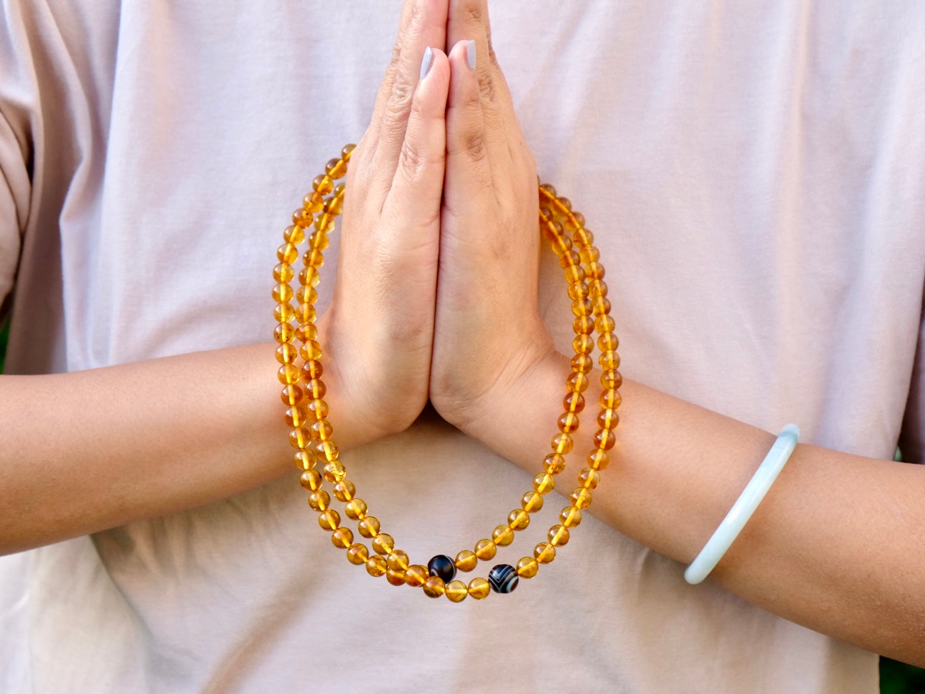 Honey amber mala in hands in Namaste gesture