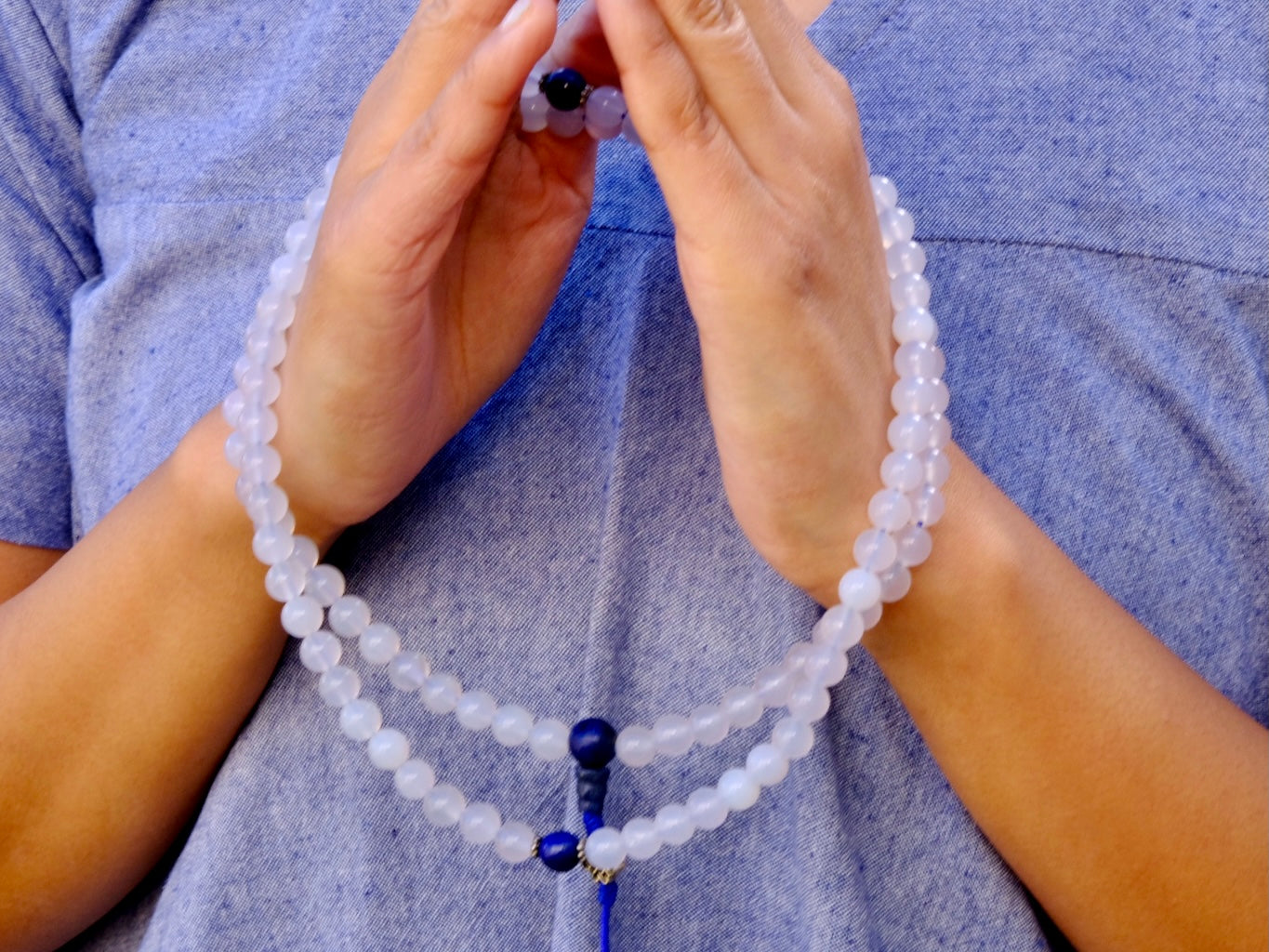 Moonstone mala around hand in namaste gesture