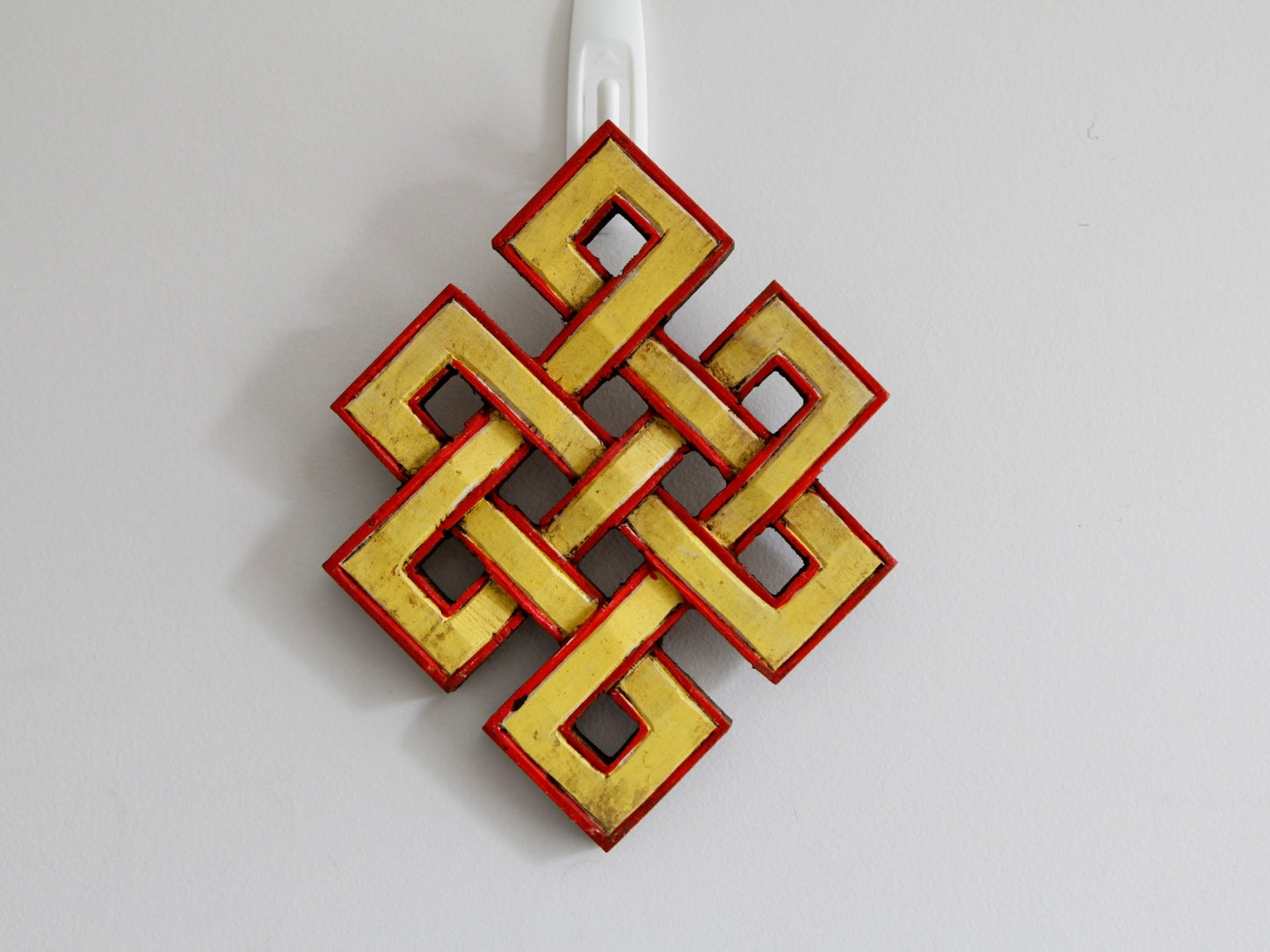 Yellow infinity knots hanging up against wall