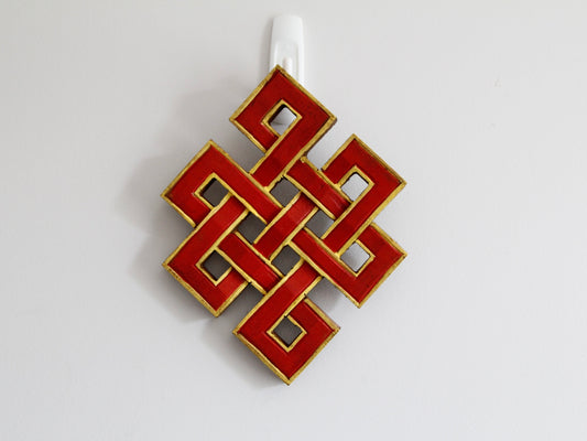 Red infinity endless knots hanging against wall