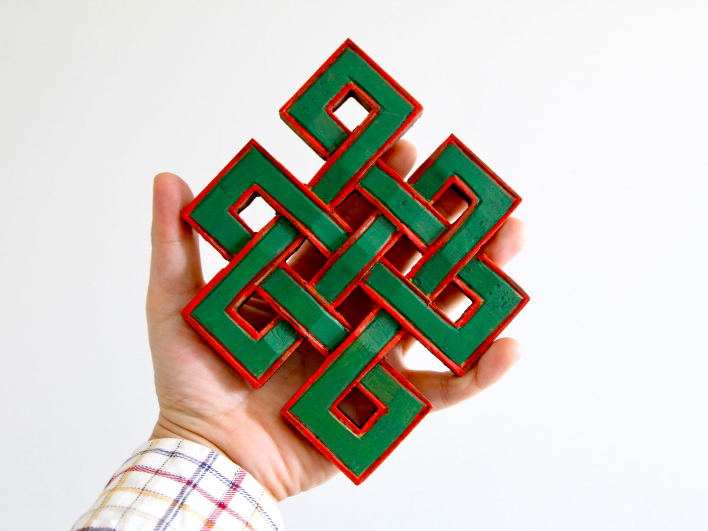 Tibetan infinity knots held on hand for size perspective