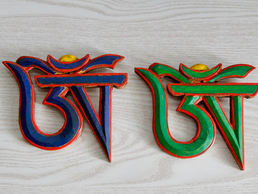 Tibetan Om wooden wall hanging in two colours against white background