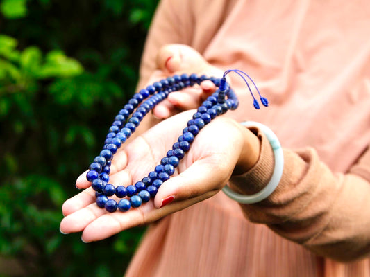 Lapis lazuli mala beads stretched out on hand showing colour