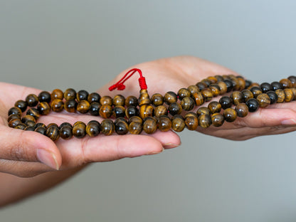 close up of tiger eye mala with red cord