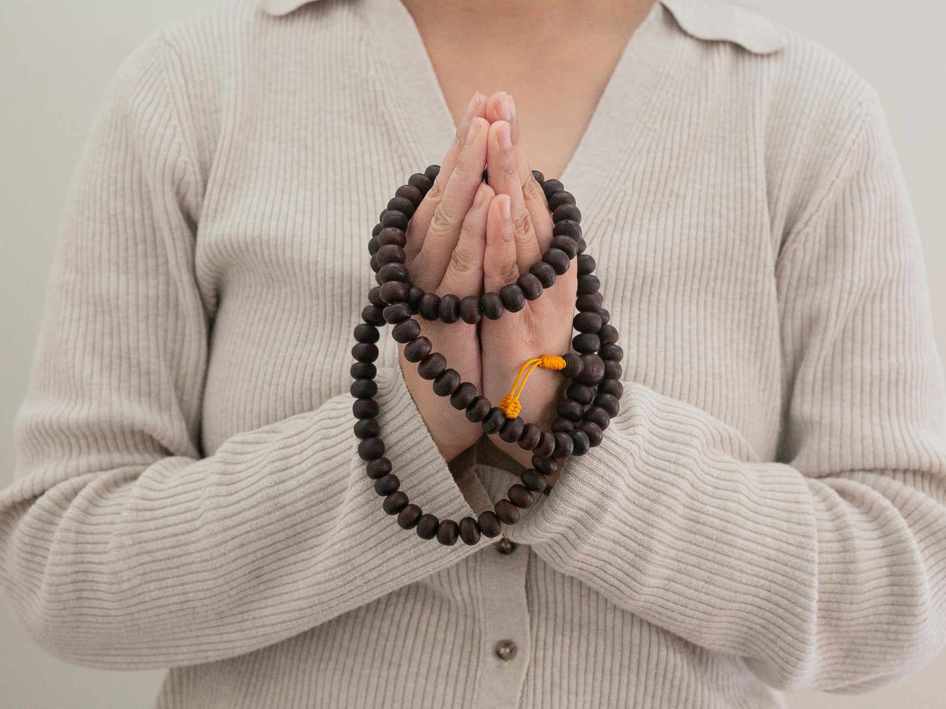 Person holding Bodhi prayer beads with a neutral background