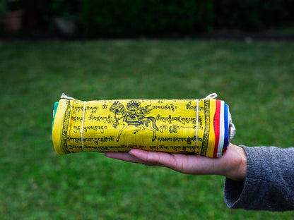 Person holding all cotton Tibetan prayer flags rolled up.