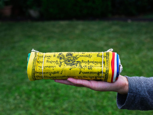 Person holding all cotton Tibetan prayer flags rolled up.