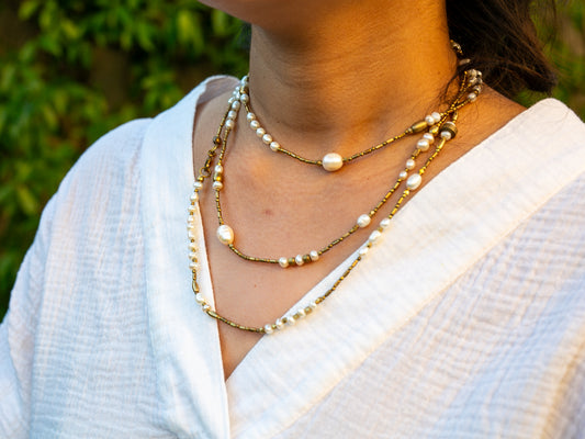 Brass and pearl necklace worn wrapped around woman's neck