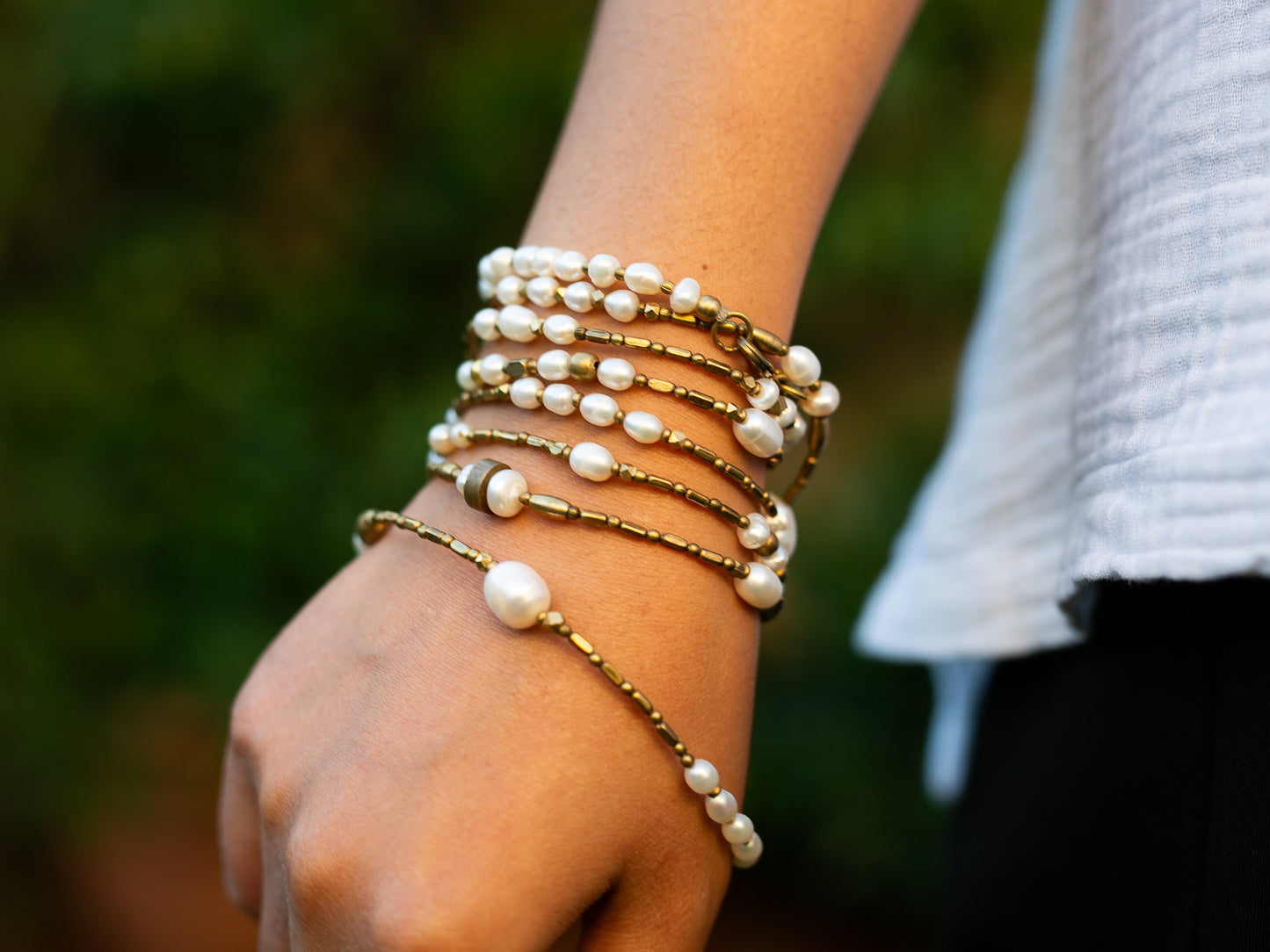 Brass and pearl necklace wrapped around hand many times