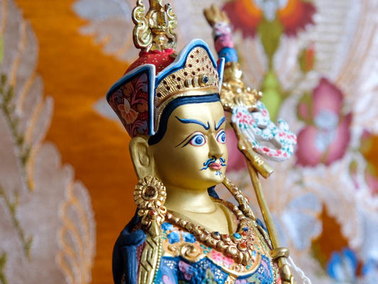 Close up of Guru Rinpoche statue showing face and painting detail