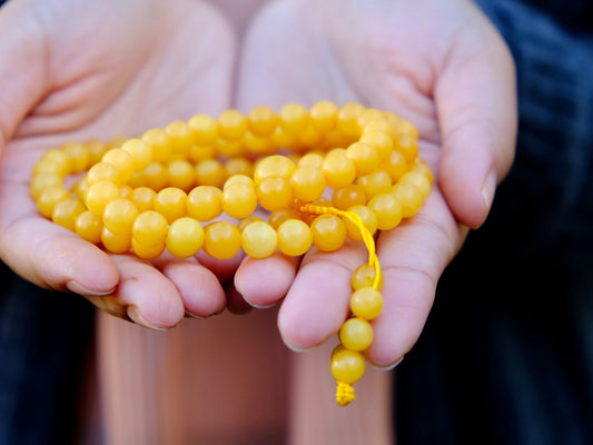 close up of amber mala with 108 beads held in hand