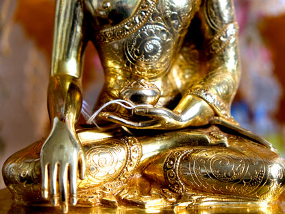 Alms bowl and detail in robes of Buddha statue