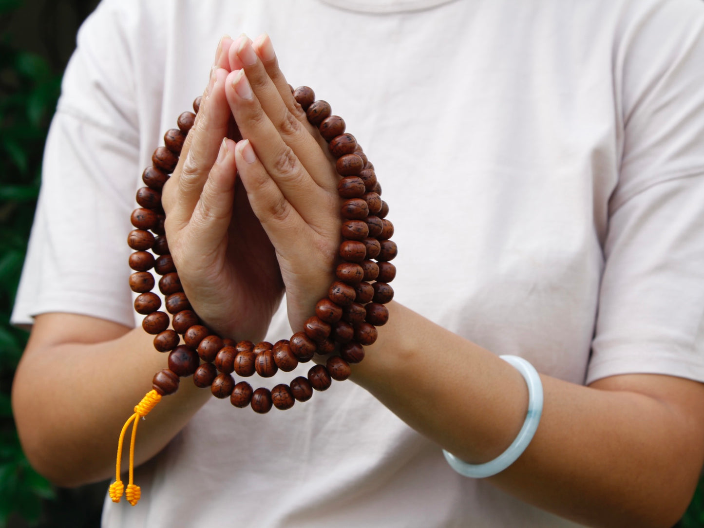 Bodhi mala wrapped around hands in Namaste gesture