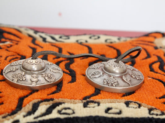 Engraved tingsha with auspicious symbols on mat