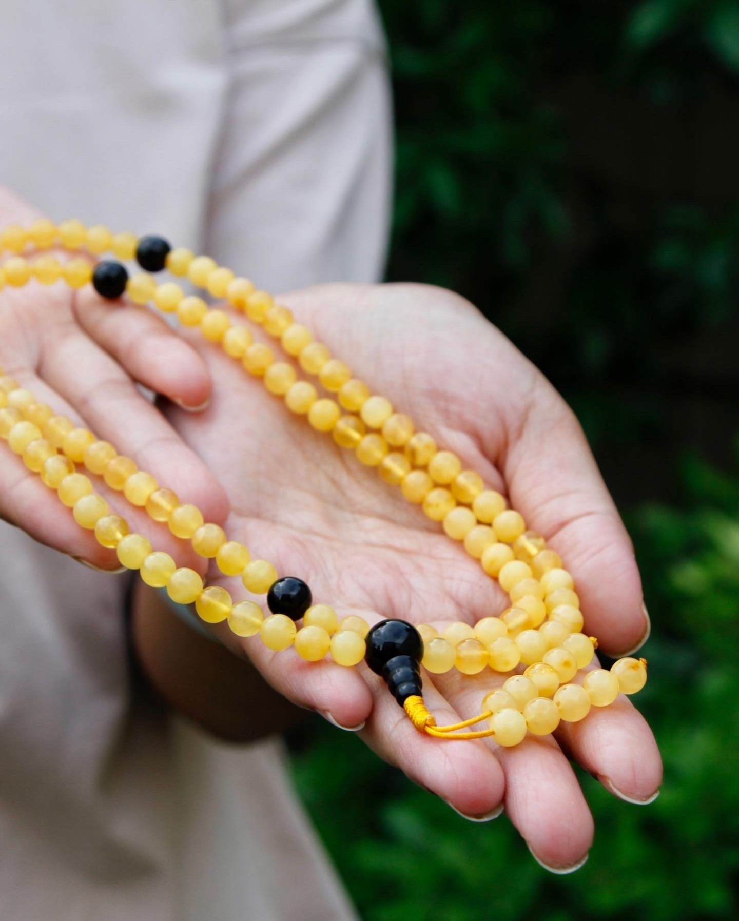 Amber mala with black tourmaline spacer beads held in hand