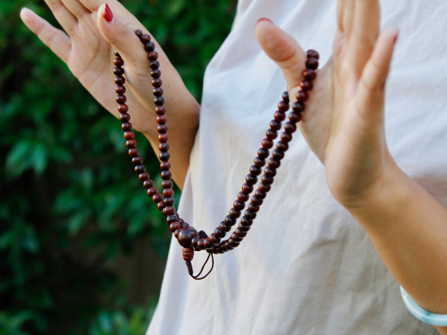 rosewood mala beads held between 2 hands showing length and shades