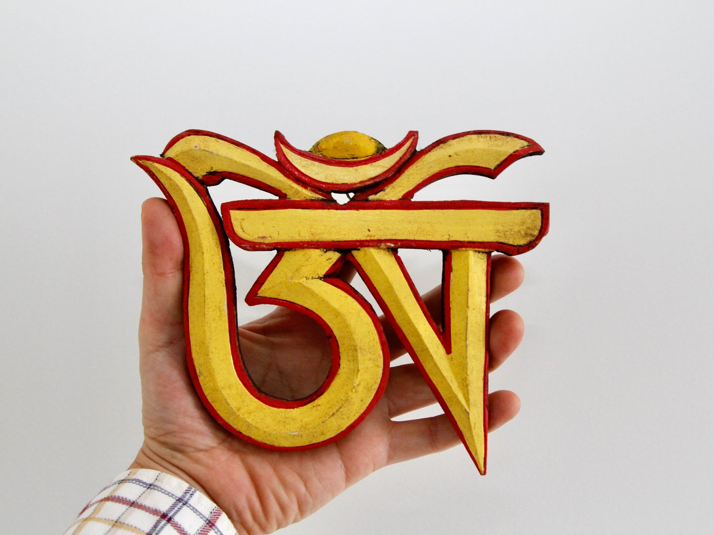 Tibetan Om wall hanging held in hand for size perspective