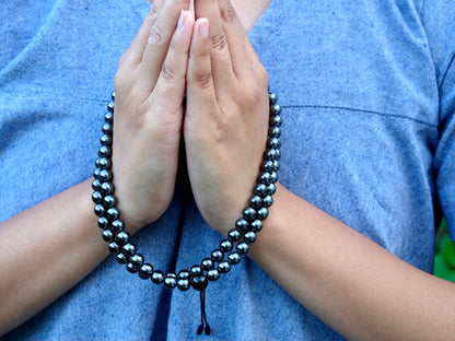 hematite mala around hands in namaste gesture