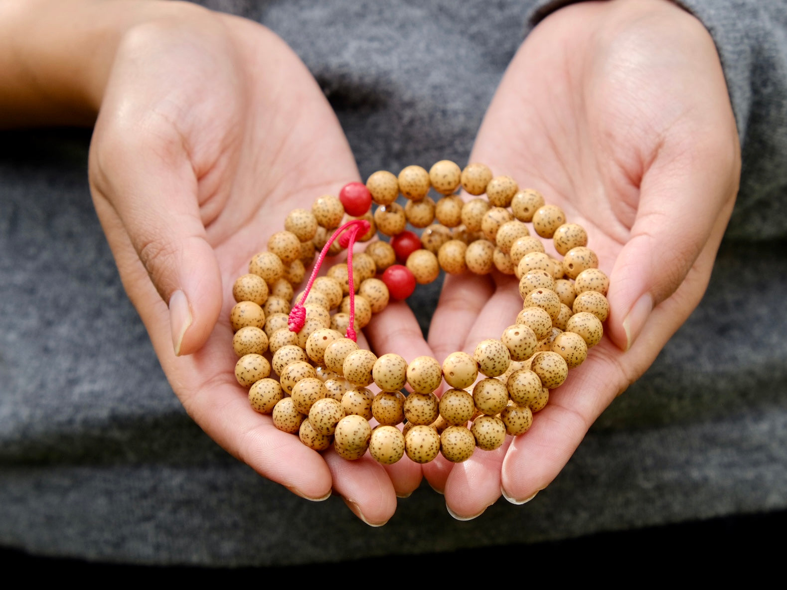 lotus seed mala with coral spacer in Kunga's hand