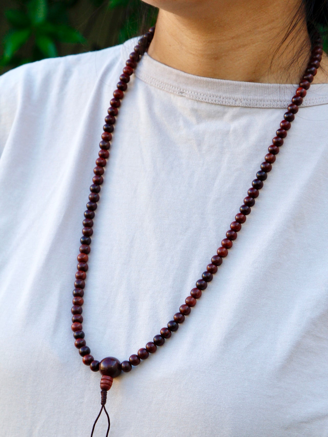 Portrait mode photo with rosewood mala beads worn around neck