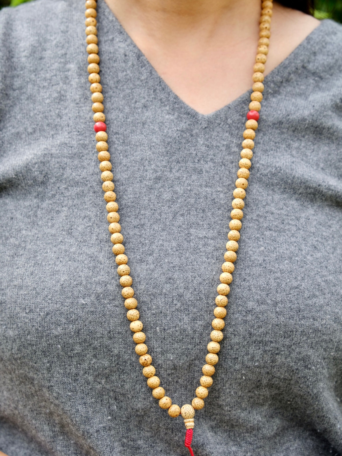 lotus seed mala with coral spacer worn around neck