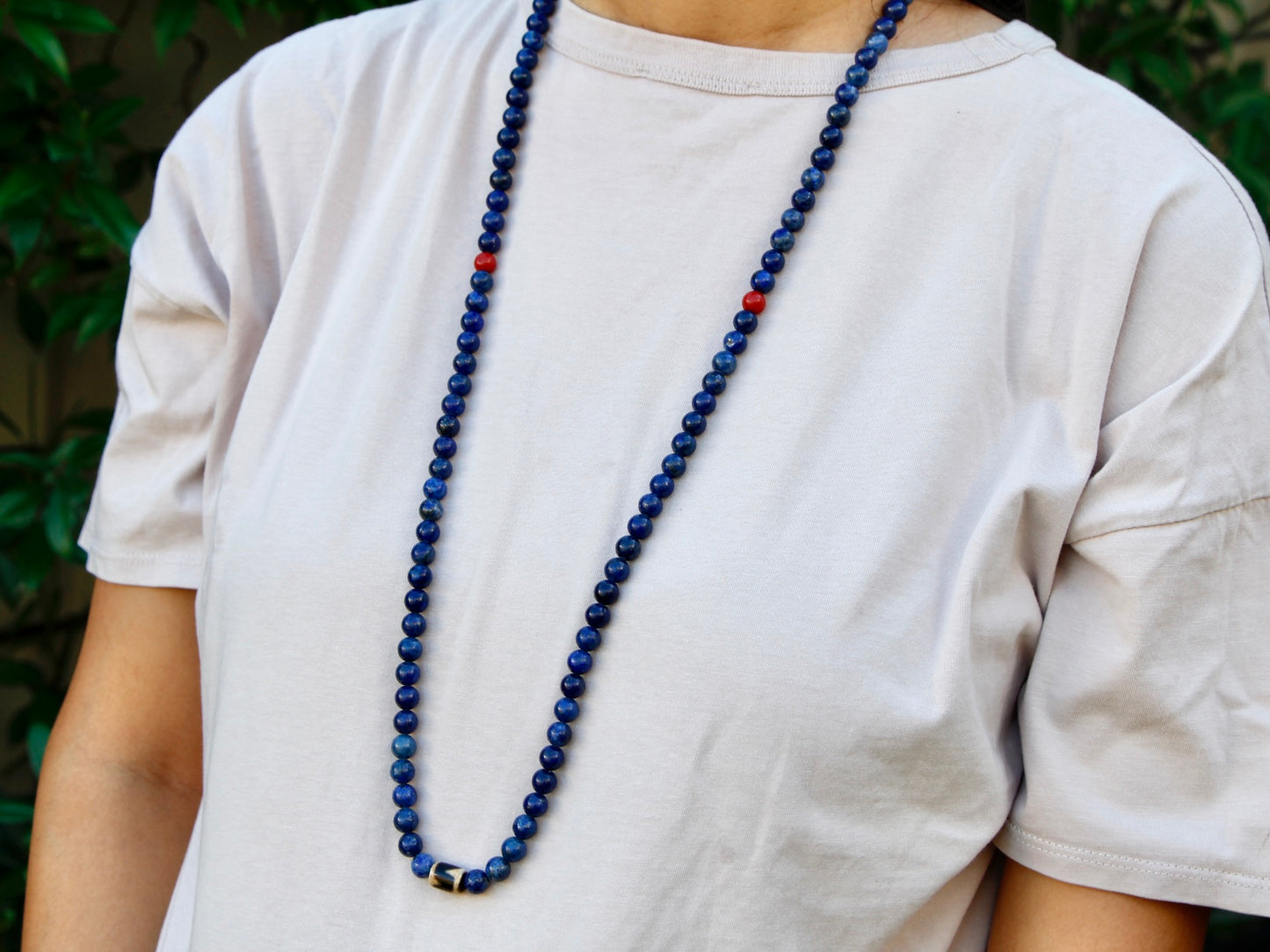 custom lapis lazuli mala worn around the neck showing coral spacers and dzi bead