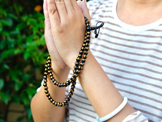 Mala beads with Om mani padme hung held in joined hands