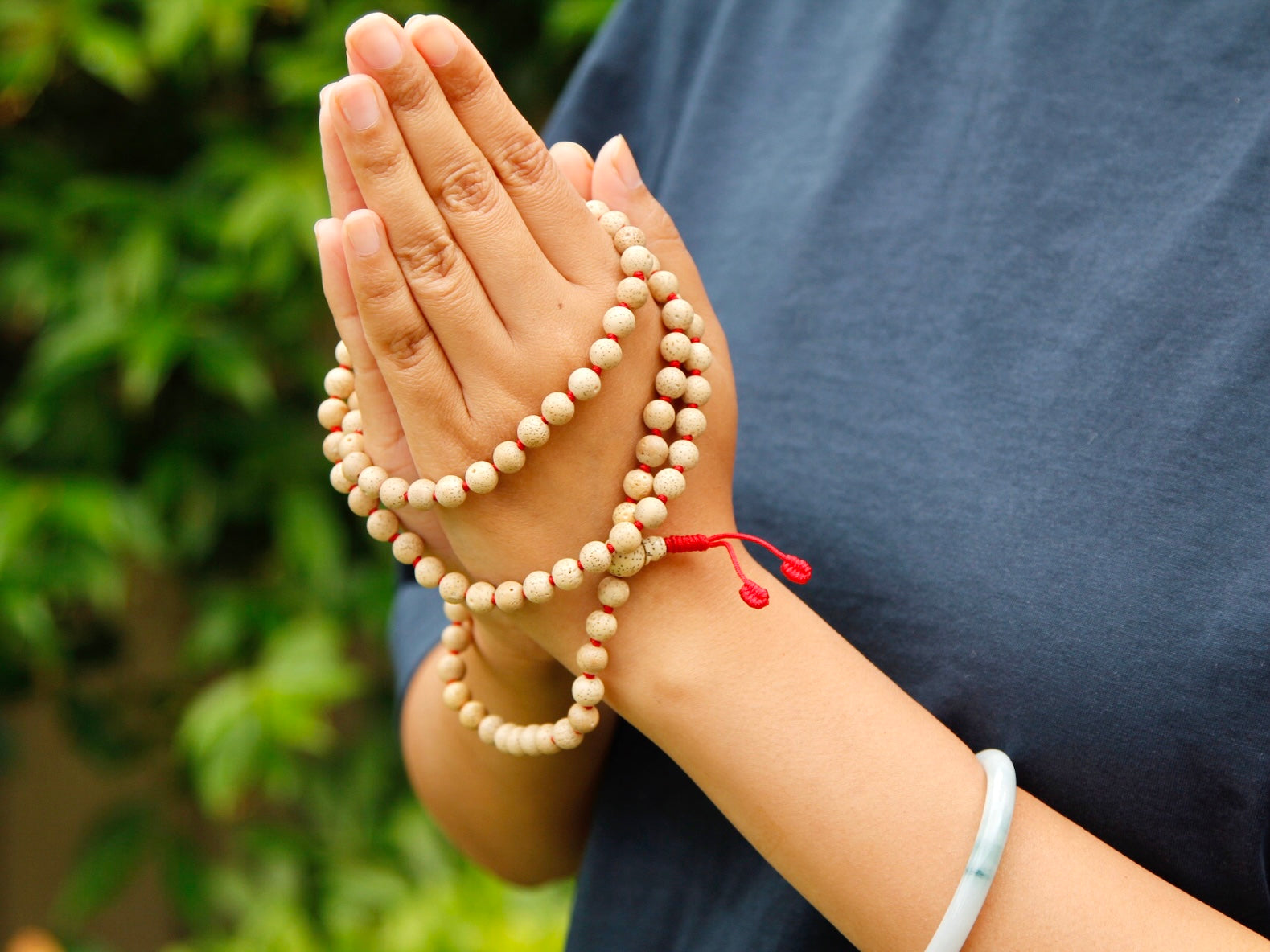 Lotus seed mala with 108 beads held in Namaste gesture