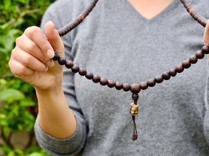 Bodhi mala beads worn around neck and held in hand