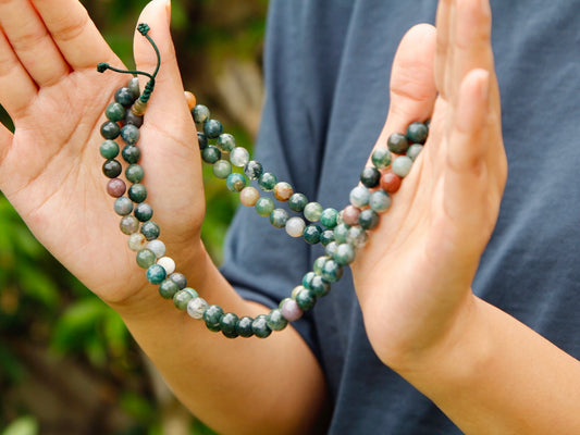 108 bead moss agate mala held in 2 hands.