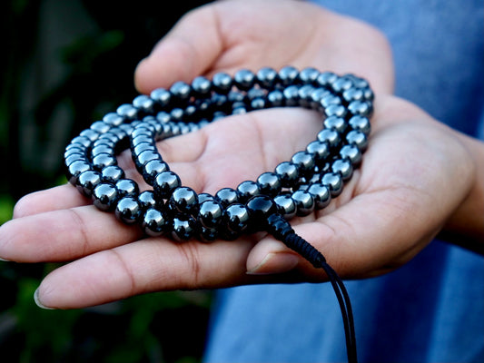 close up of hematite mala with 108 beads held in Kunga's palm